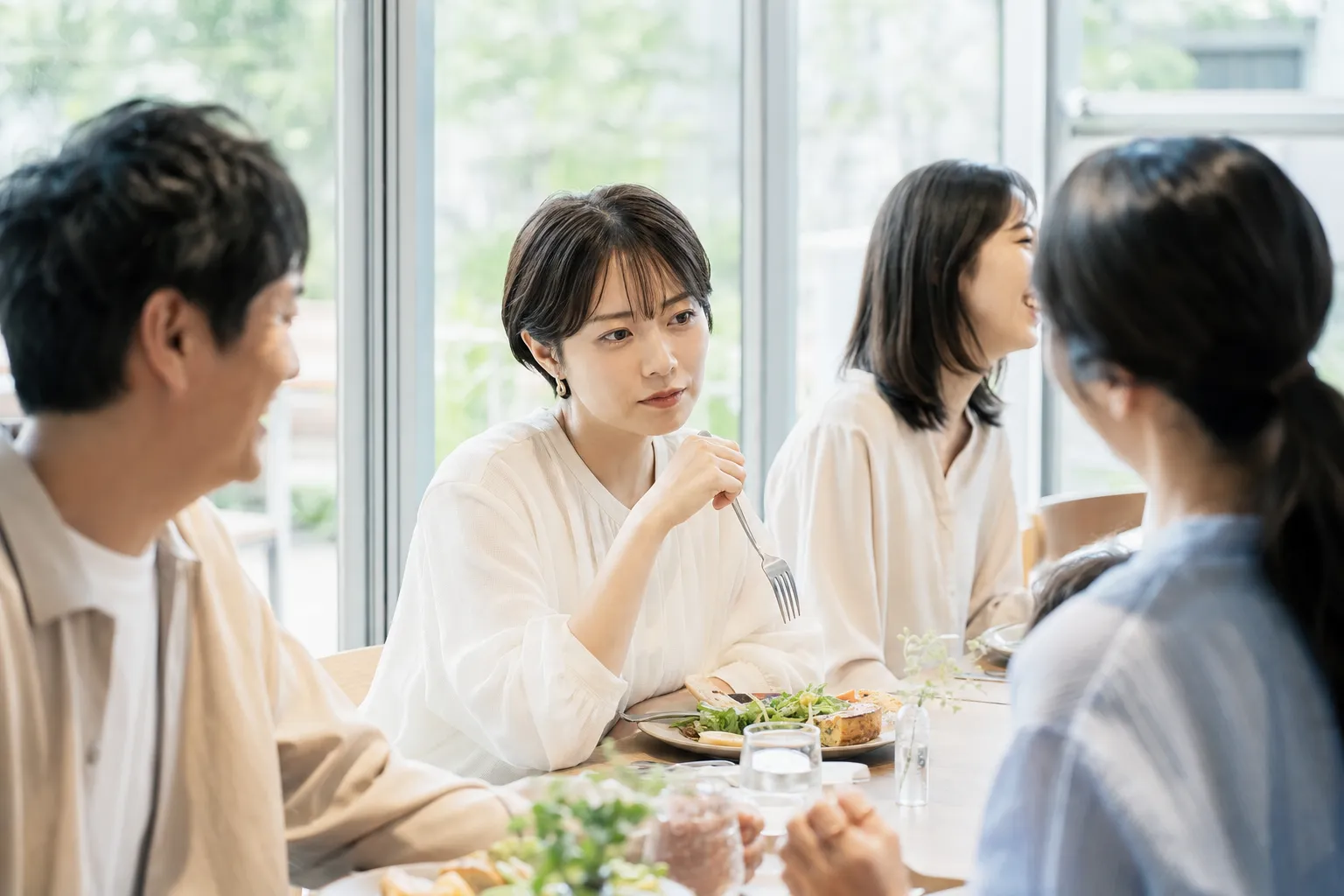 食事会で子どもの話題に言葉を選ぶ30代女性
